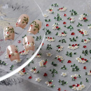 Macro detail of 3D embossed nail stickers featuring white flowers and red berries