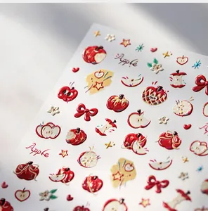 Macro shot of 3D embossed apple nail art stickers with red bows and gold accents