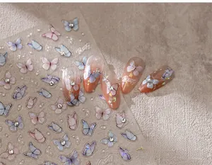Macro shot of 3D butterfly nail stickers with blue-pink gradients and tiny rhinestones