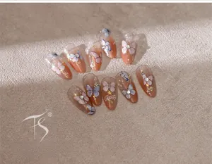 Macro shot of 3D butterfly nail stickers with gold foil and rhinestones on pink gradient