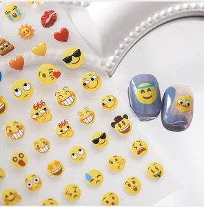 Detail of emoji nail stickers featuring smiley faces and 666 patterns on clear film