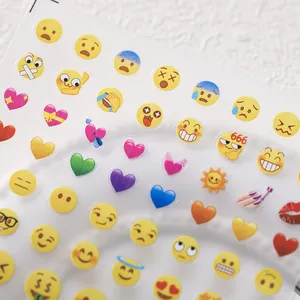 Cute emoji nail art stickers with heart patterns on a transparent adhesive sheet