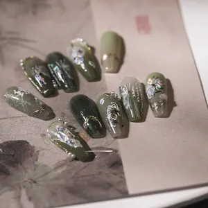 Macro detail of handmade 3D press-on nails with green cat-eye and floral art patterns