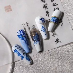 Detailed close-up of blue and white porcelain style press-on nails with lotus and calligraphy