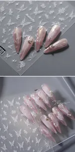 Detail of 5D butterfly nail stickers on long pink gradient nails with pearl accents