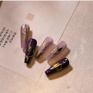Detail of purple and pink long coffin press-on nails with gold butterfly patterns