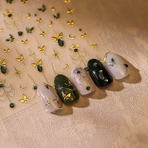 Detailed close-up of gold butterfly nail stickers with green gemstone accents