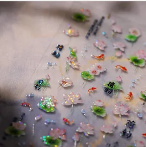 Macro detail of bronzing nail stickers with lotus, koi fish, and shimmer laser finish