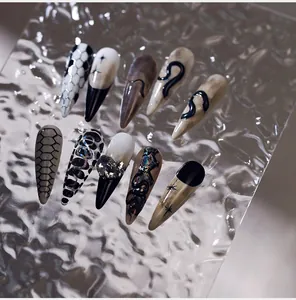 Détail d'ongles stiletto style serpent avec écailles peintes à la main et strass argentés