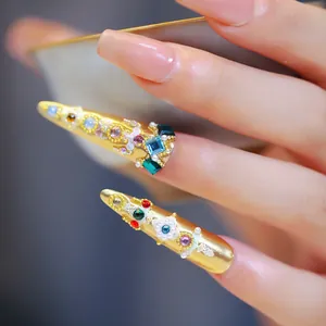 Faux ongles stiletto dorés avec strass colorés, perles et pierres géométriques
