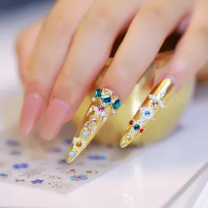 Faux ongles stiletto dorés avec strass colorés, perles et autocollants aux motifs floraux