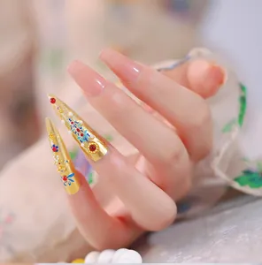 Detailed view of luxury gold stiletto nail art with royal beads and pink coffin nails