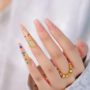 Close-up of gold filigree nail stickers with colorful gems and jelly pink finish