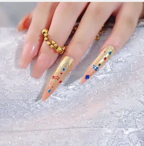 Detailed macro of stiletto gold leaf nail stickers with rhinestones and floral patterns