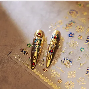 Detailed macro view of vintage gold nail art stickers with red and blue gemstone accents