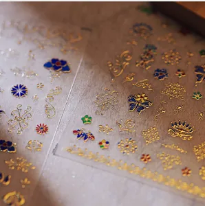 Macro detail of Chinese retro gold foil nail stickers with lotus and butterfly patterns