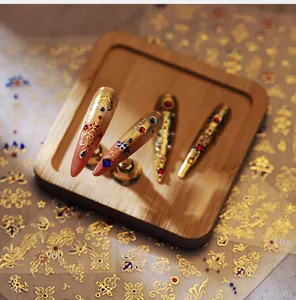 Detail of gold embossed nail stickers with vintage floral patterns and gemstone accents