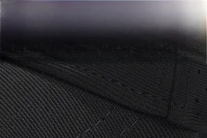 Detail of the twill texture and reinforced double-row stitching on a black baseball cap