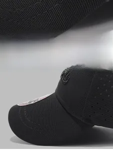 Detail of a black baseball cap with laser-cut ventilation holes and precise stitching