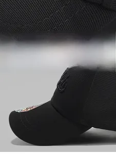Détail de casquette noire montrant le bord à triple couture et la broderie 3D de couronne