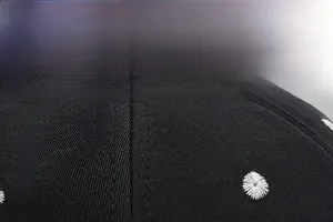 Detailed close-up of high-quality twill fabric and white daisy embroidery on a black cap
