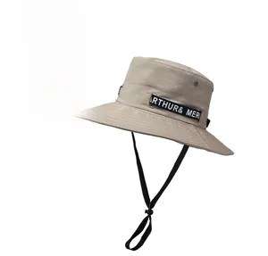 Detail of khaki bucket hat with adjustable chin strap and lettered ribbon tag