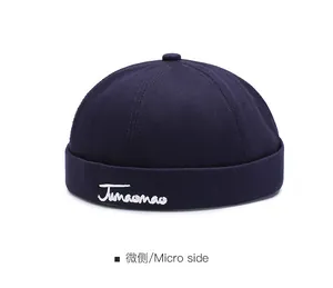 Dettaglio del cappello docker blu scuro con ricamo bianco Junaomao artistico