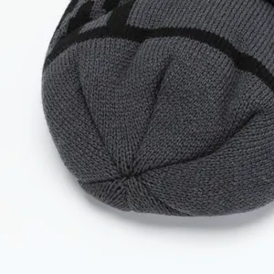 Close-up of winter knit beanie showing thick grey and black yarn with textured stitching
