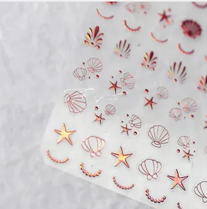 Détails macro d'autocollants nail art 3D or rose avec motifs de coquillages et étoiles