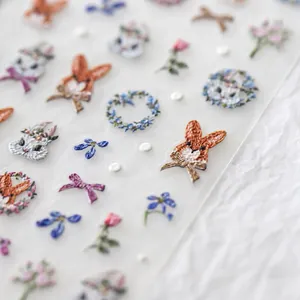 Makro-Detail von 5D-Nagelstickern mit realistischen Stickerei-Hasen und Blumenmustern