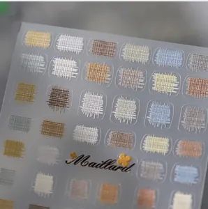 Macro shot of Maillard-style plaid and weave patterns on professional nail art stickers