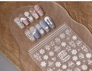 Detailed macro of 3D embossed Christmas nail stickers featuring white snowflakes and reindeers