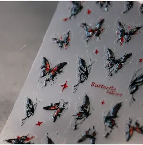 Macro shot of 5D butterfly nail stickers featuring red and black gothic relief texture