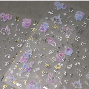 Detailed close-up of zodiac nail art stickers with metallic gold and purple starry patterns