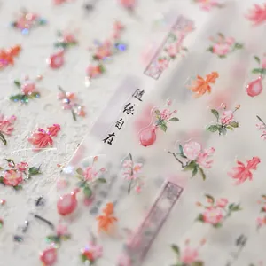 Macro detail of nail stickers with pink flowers, red goldfish, and calligraphy designs