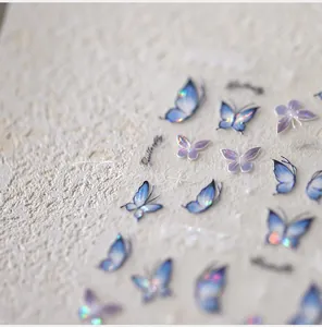 Macro shot of holographic purple butterfly nail decals with iridescent blue glitter texture