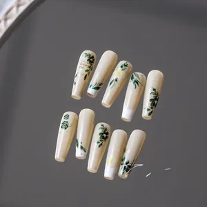 Detail view of almond milk nails with dark green floral patterns and hand-painted art