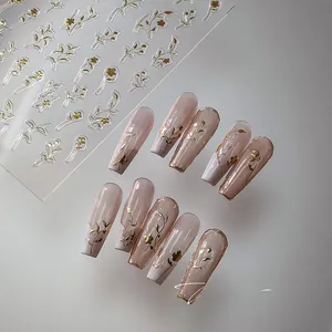 Macro detail of M-332 gold embossed floral nail stickers on pink ballet shape nails