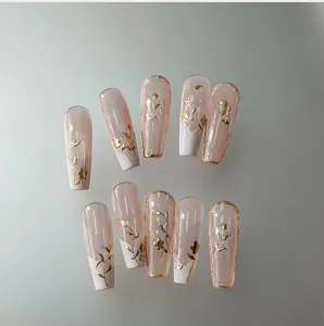 Detailed view of long coffin nails with gold embossed floral patterns and French tips