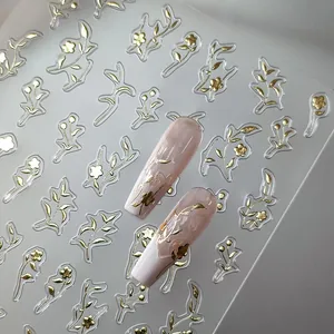 Golden floral nail art stickers with delicate leaf designs on pink gradient nails