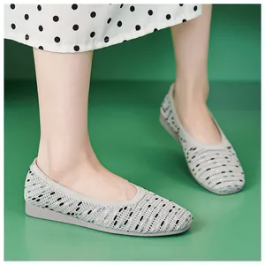 Close-up of breathable grey knitted flat shoes with mixed green and black spot patterns