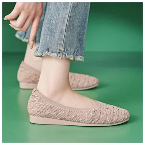 Close-up of nude pink knitted mesh flat shoes with breathable texture on a green background