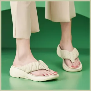 Details von beigen Plateau-Flip-Flops mit gerafften Riemen und dicker Keilsohle