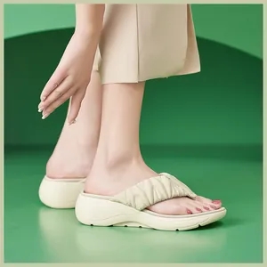 Detail von beigen Plateau-Flip-Flops mit gesteppter Faltenstruktur und dicker MD-Sohle