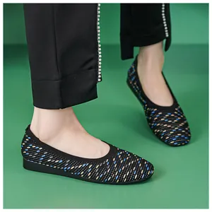 Flat knit shoes with dotted pattern on model wearing black trousers and pearls
