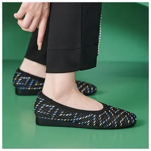 Detail view of breathable knit flat shoes with multi-color pattern on green background