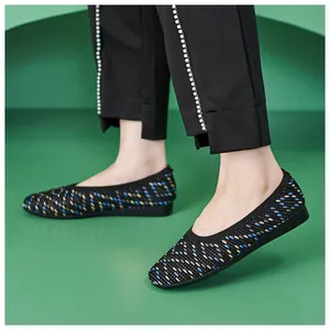 Detail of knitted women flat shoes with blue and beige polka dots on green background