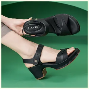 Detail of black block heel sandals with crisscross straps and metal buckle closure
