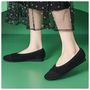 Detail of black faux fur and knit flat shoes paired with a black floral mesh skirt
