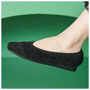 Close-up of black knitted plush flat shoes with jacquard pattern and rubber sole